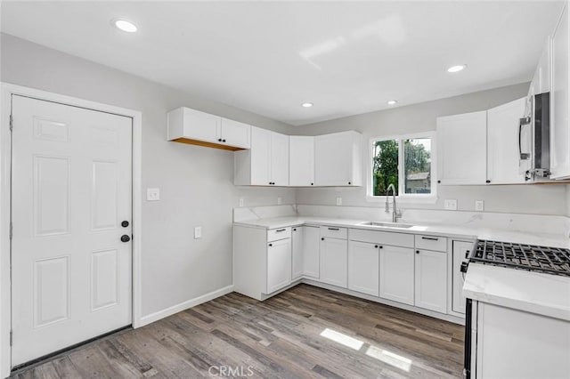 kitchen featuring white cabinetry, light countertops, a sink, and wood finished floors