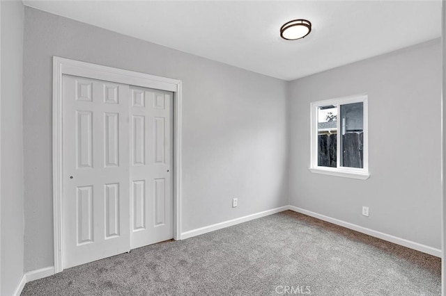unfurnished bedroom with carpet, a closet, and baseboards