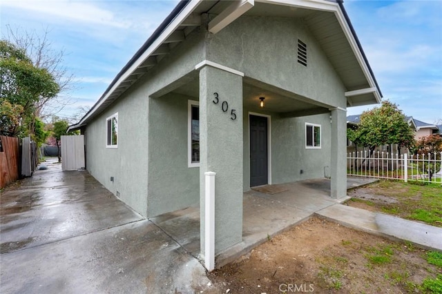 view of front of home with stucco siding, fence, and a patio