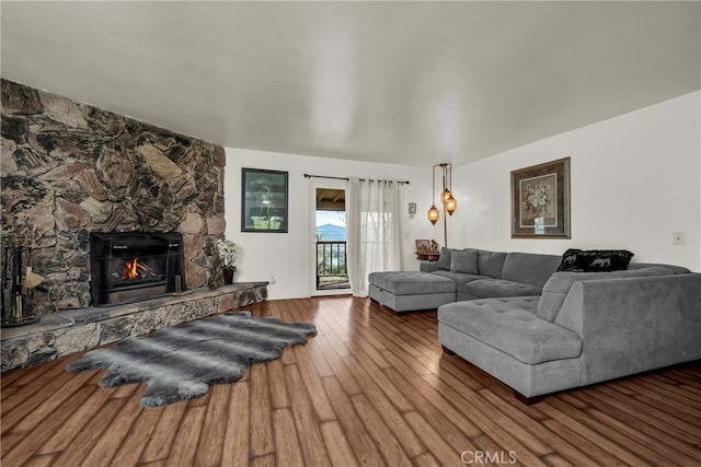 living room featuring a stone fireplace and wood finished floors