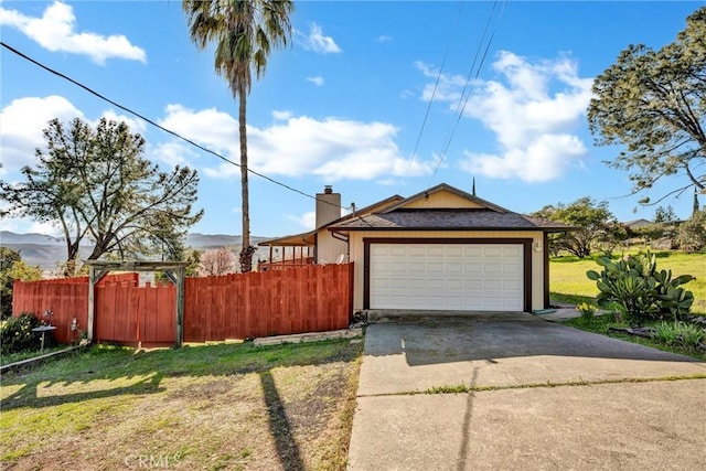 exterior space with a chimney, concrete driveway, a yard, and fence