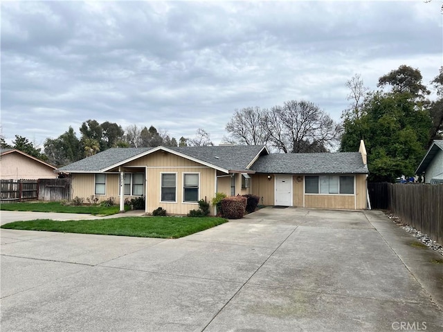 ranch-style house featuring concrete driveway, fence, and a front lawn