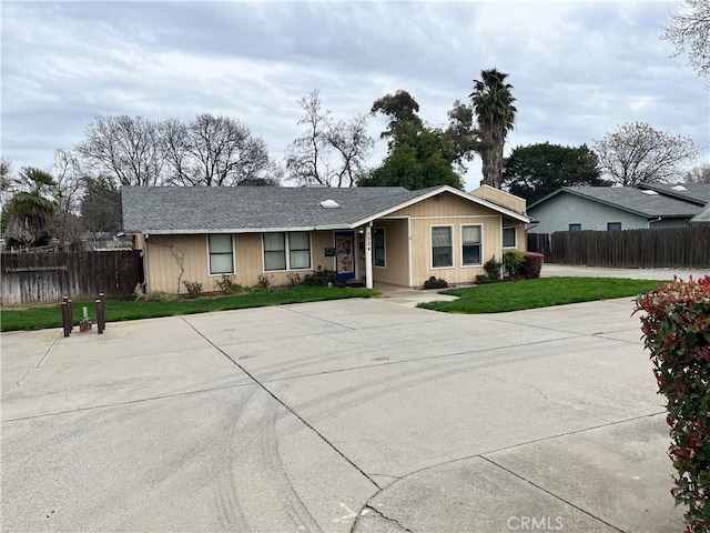 ranch-style house with driveway, a front lawn, and fence