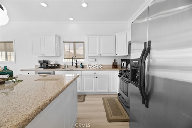 kitchen with white cabinets, appliances with stainless steel finishes, and crown molding