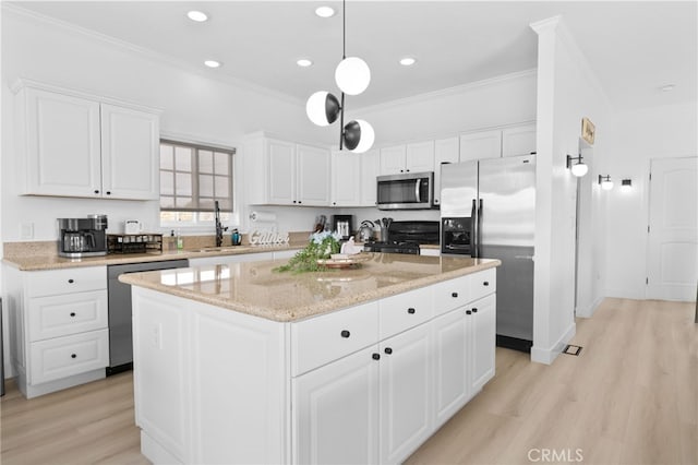 kitchen featuring a kitchen island, crown molding, appliances with stainless steel finishes, white cabinets, and a sink