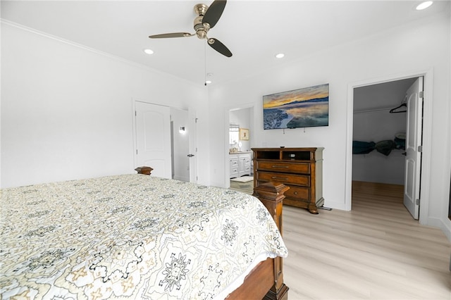 bedroom with a spacious closet, recessed lighting, and light wood finished floors