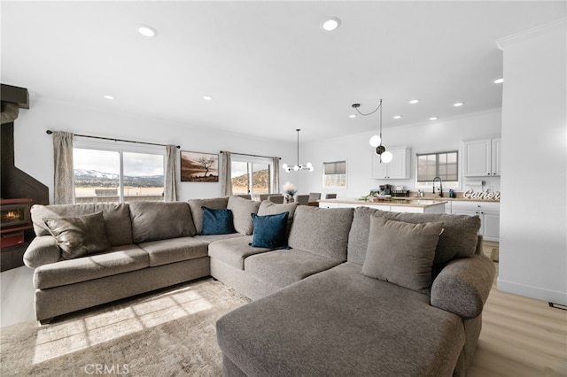 living area with baseboards, a wood stove, recessed lighting, crown molding, and light wood-type flooring