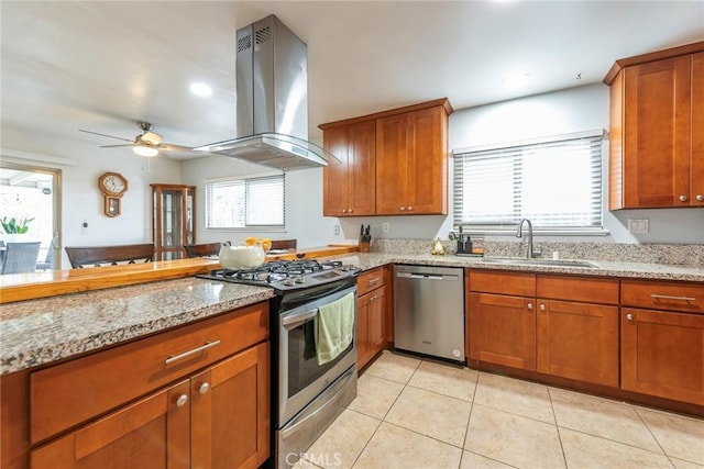 kitchen featuring island exhaust hood, stainless steel appliances, brown cabinets, and a sink