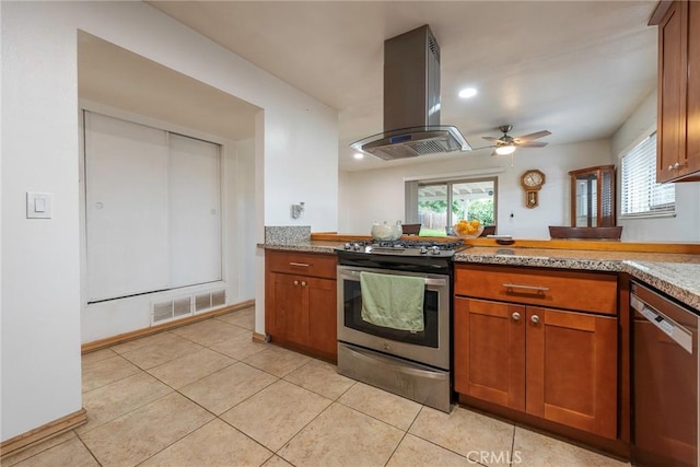 kitchen featuring visible vents, island exhaust hood, brown cabinetry, stainless steel appliances, and a ceiling fan