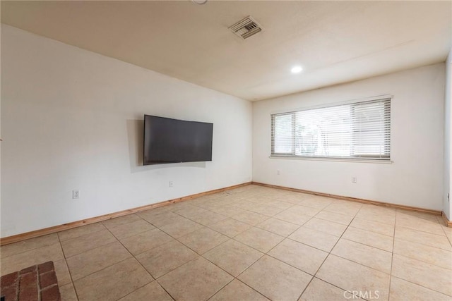 empty room with light tile patterned flooring, visible vents, and baseboards