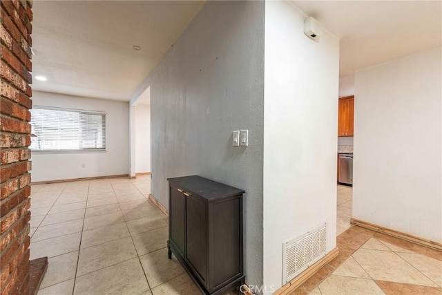 corridor featuring light tile patterned flooring, baseboards, and visible vents