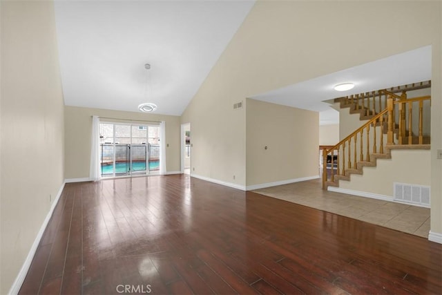 unfurnished living room featuring visible vents, baseboards, high vaulted ceiling, and hardwood / wood-style floors