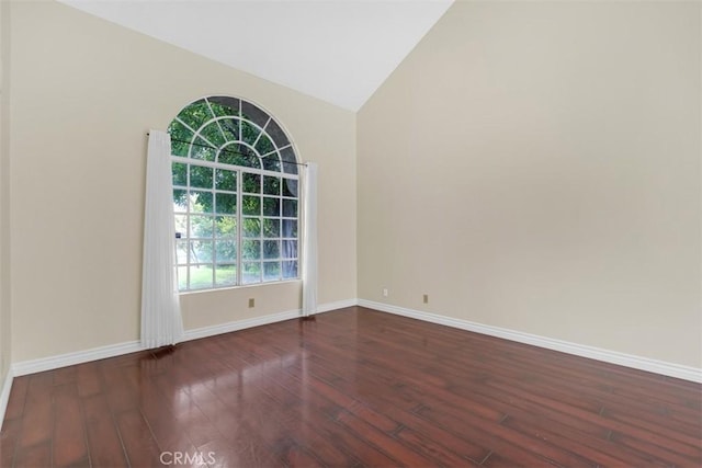 unfurnished room with baseboards, wood finished floors, and vaulted ceiling