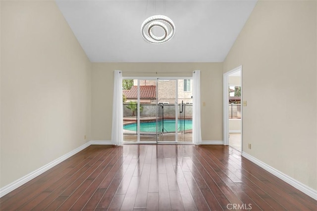 spare room featuring baseboards, a notable chandelier, dark wood finished floors, and high vaulted ceiling