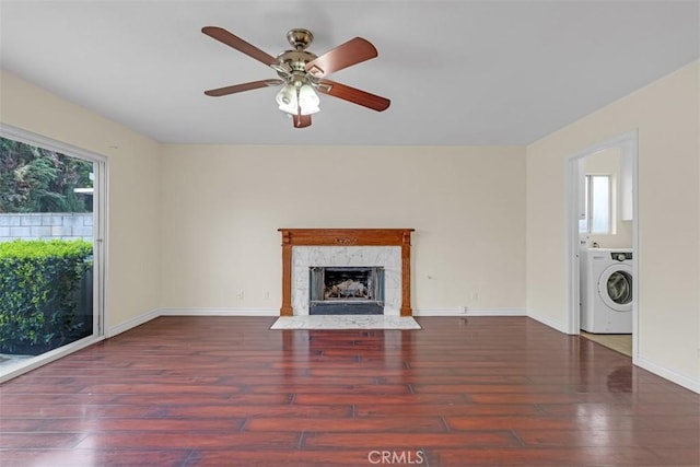 unfurnished living room with a high end fireplace, baseboards, hardwood / wood-style flooring, washer / clothes dryer, and a ceiling fan