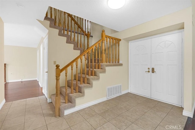 stairway featuring tile patterned floors, baseboards, and visible vents