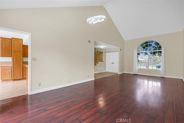 unfurnished living room featuring visible vents, baseboards, and wood finished floors