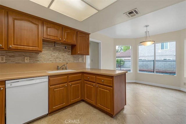 kitchen with a sink, brown cabinets, light countertops, and white dishwasher