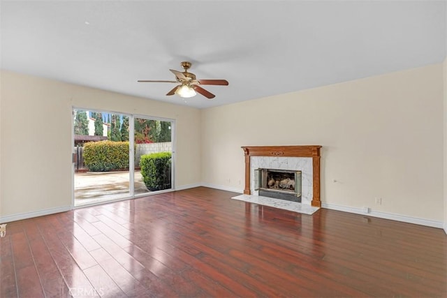 unfurnished living room with a fireplace, baseboards, ceiling fan, and wood finished floors