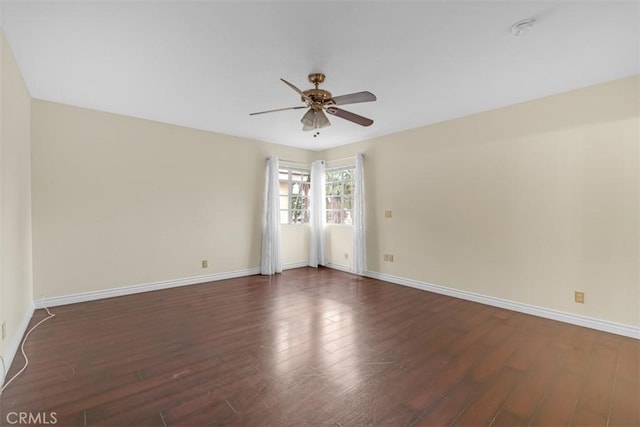 empty room featuring baseboards, dark wood-style floors, and a ceiling fan