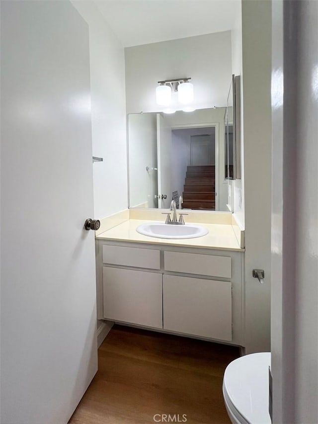 bathroom with toilet, wood finished floors, and vanity