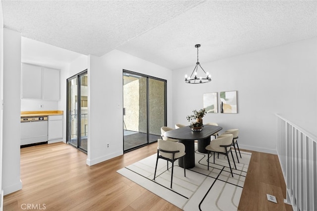 dining room featuring a notable chandelier, baseboards, light wood finished floors, and a textured ceiling