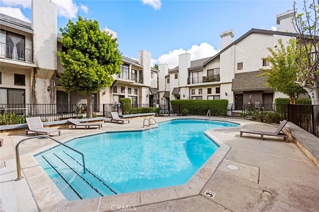 community pool with a residential view, a patio, and fence