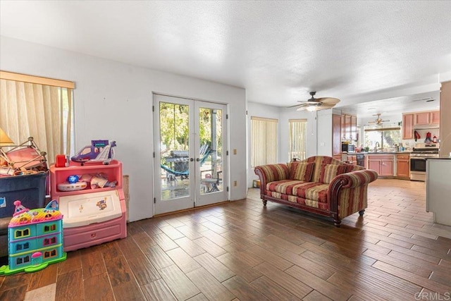 living room featuring french doors, a textured ceiling, ceiling fan, and wood finished floors