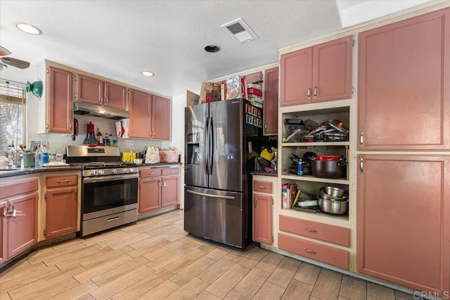 kitchen featuring dark countertops, visible vents, under cabinet range hood, appliances with stainless steel finishes, and light wood-style floors