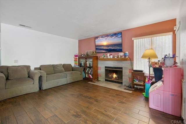 living room featuring wood finished floors, visible vents, and a tile fireplace