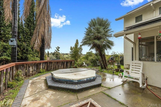 wooden deck featuring a patio, a covered hot tub, and fence