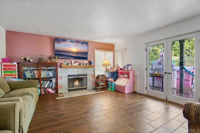 living room with wood finish floors, french doors, a textured ceiling, and a fireplace