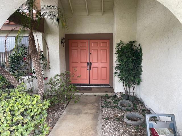 doorway to property featuring stucco siding