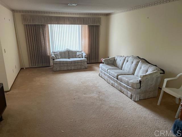 living room featuring visible vents, carpet flooring, and crown molding