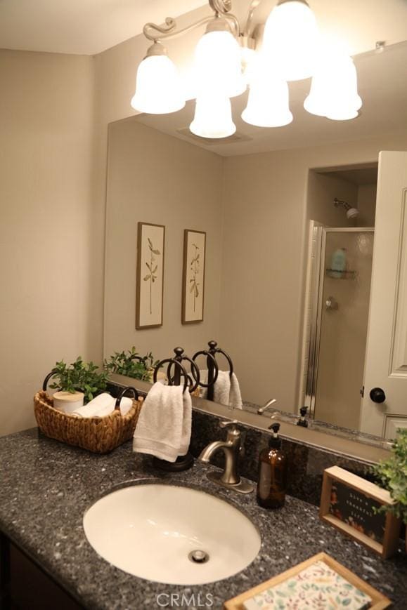 bathroom with a stall shower, vanity, and an inviting chandelier