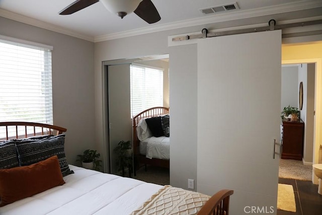 bedroom with visible vents, ceiling fan, a barn door, and ornamental molding