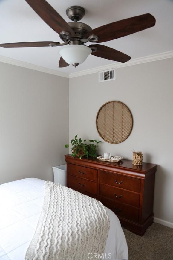 carpeted bedroom featuring visible vents, baseboards, a ceiling fan, and ornamental molding