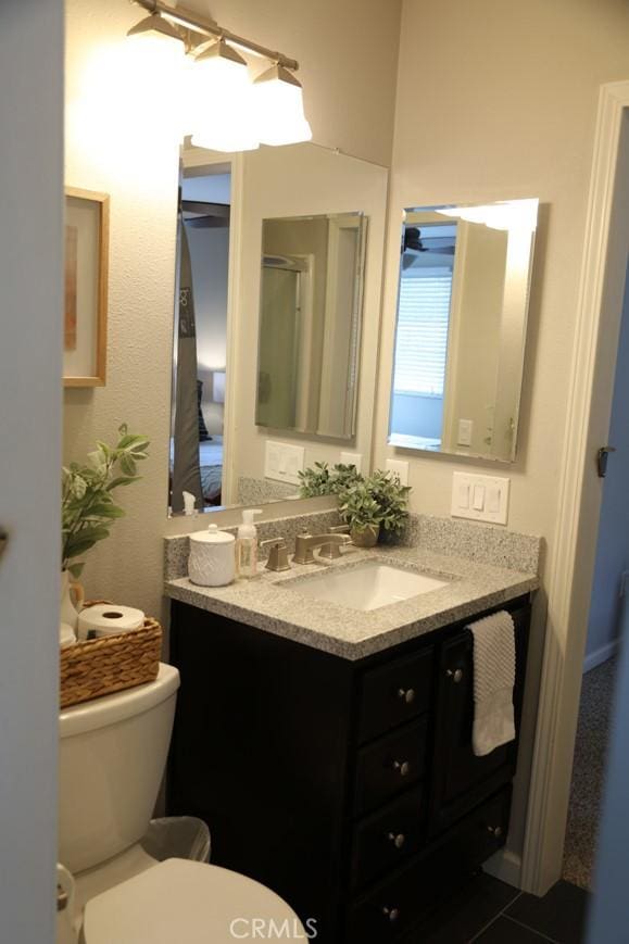 bathroom with toilet, vanity, and a shower with shower door