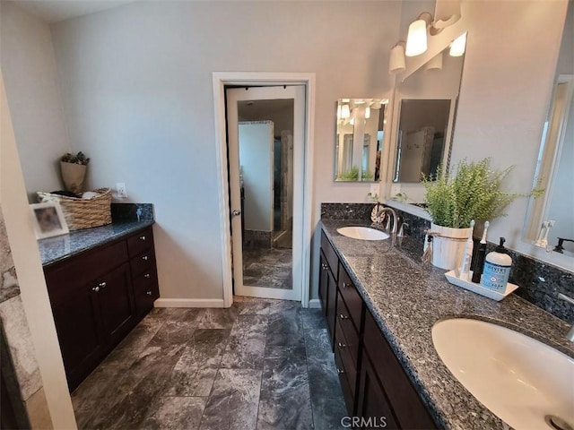 bathroom with a sink, baseboards, and double vanity