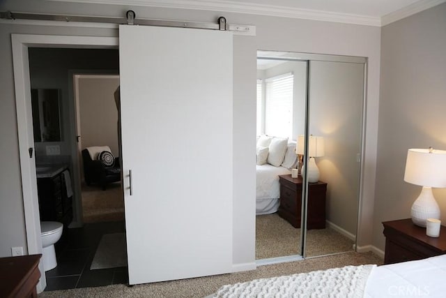 bedroom with baseboards, carpet floors, a barn door, a closet, and crown molding