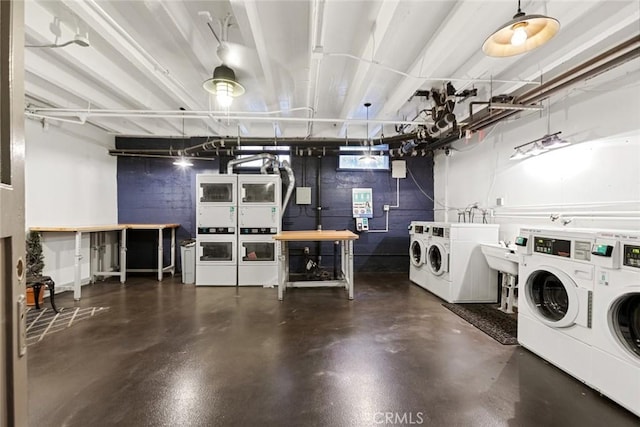 community laundry room with independent washer and dryer, stacked washing maching and dryer, and concrete block wall