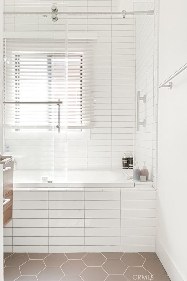 bathroom featuring a relaxing tiled tub, tile patterned flooring, and a tile shower