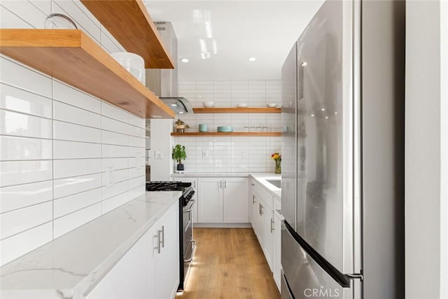 kitchen with open shelves, freestanding refrigerator, decorative backsplash, white cabinets, and range with gas cooktop