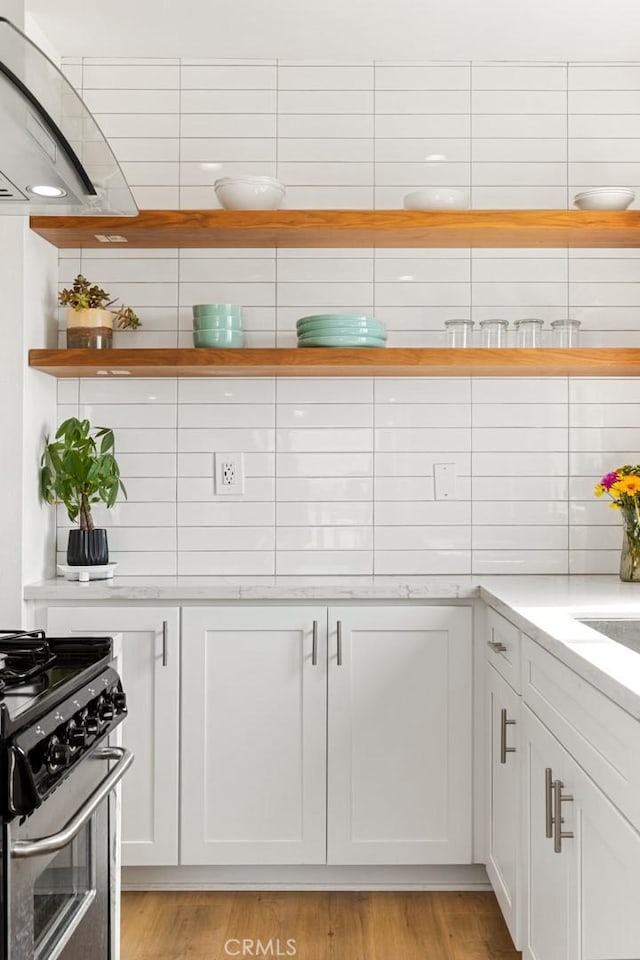 kitchen with white cabinetry, open shelves, light wood-style flooring, and stainless steel range with gas cooktop