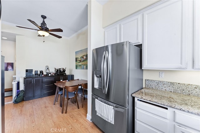 kitchen with ceiling fan, ornamental molding, light wood-style flooring, stainless steel refrigerator with ice dispenser, and white cabinets