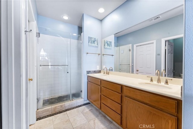 bathroom featuring double vanity, visible vents, a stall shower, and a sink