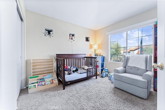 bedroom with a nursery area and carpet flooring