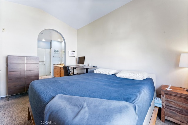 carpeted bedroom with vaulted ceiling and arched walkways