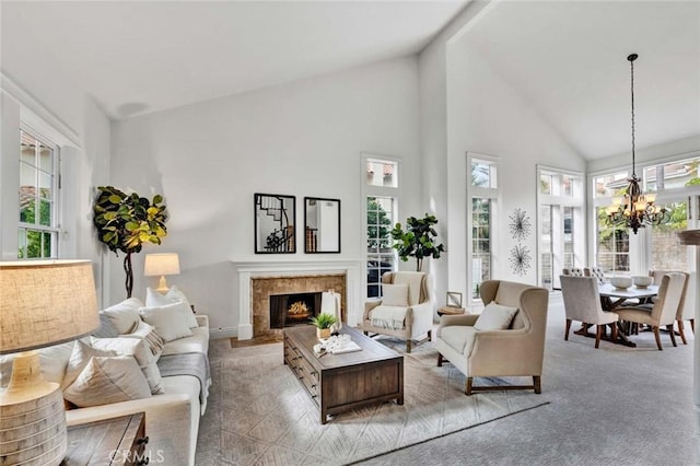 carpeted living room with a premium fireplace, high vaulted ceiling, and a chandelier