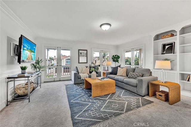 carpeted living room with a healthy amount of sunlight, french doors, built in shelves, and ornamental molding